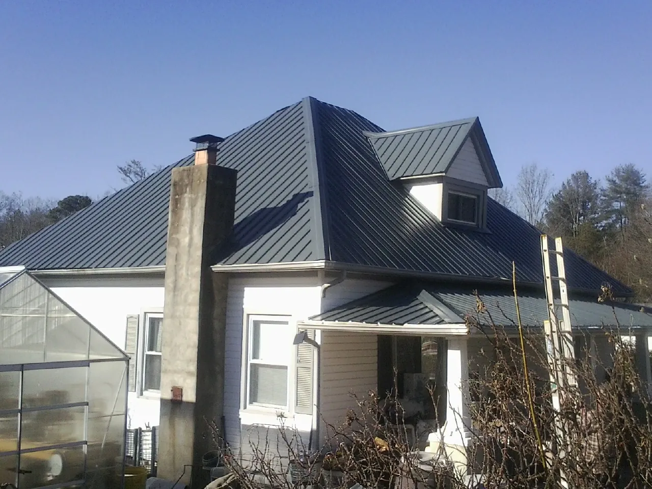 Dark blue standing seam metal roof on a white farmhouse with dormer — Slate & Tile Roof Repair by Roofing Brothers in Cos Cob