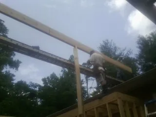 Carpenter setting a ridge beam over a new addition frame — Ice Dam Removal by Roofing Brothers in Cos Cob
