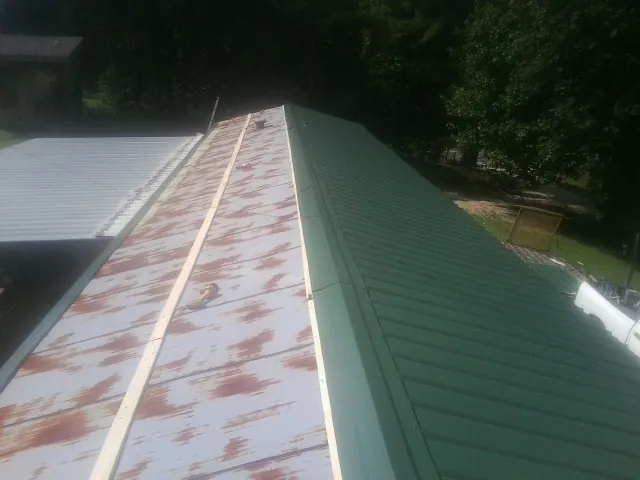 Old rusted panels beside newly installed green metal roofing — Wind Damage Roof Repair by Roofing Brothers in Cos Cob