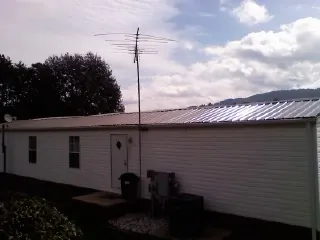 New metal roof on a single wide mobile home with a TV antenna in Cos Cob
