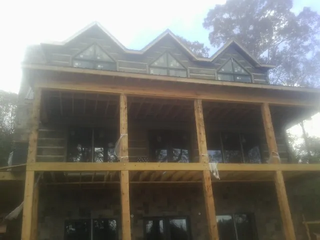 Dormers and porch framing on a large log home under construction — Roof Coating work by our crew in Cos Cob