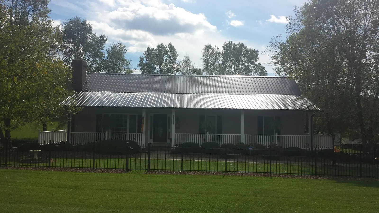 Gray metal roof on a brick ranch with a full width front porch — Gutter Guard Installation work by our crew in Cos Cob